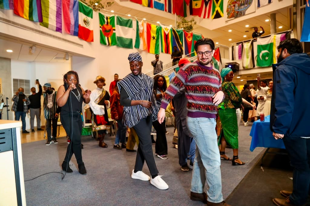 Students dancing together beneath rows of national flags at an international festival